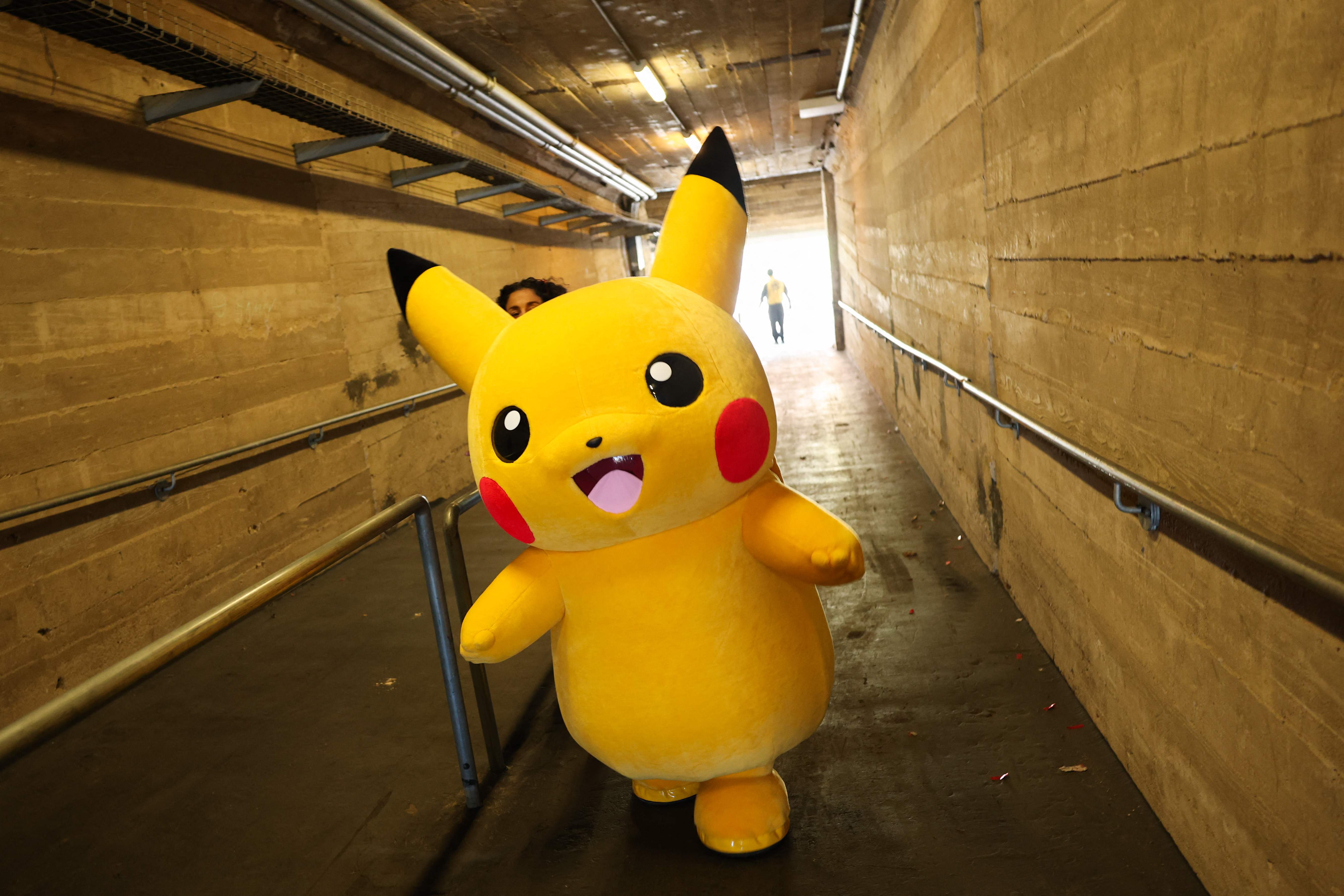 Un personaje de Pikachu camina por un túnel tras posar para fotos con fans mientras juegan Pokémon GO en sus smartphones durante el evento presencial Pokémon GO Tour: Kalos Los Ángeles 2026 en el Estadio Rose Bowl de Pasadena, California, el 20 de febrero de 2026. (Foto Prensa Libre: AFP)