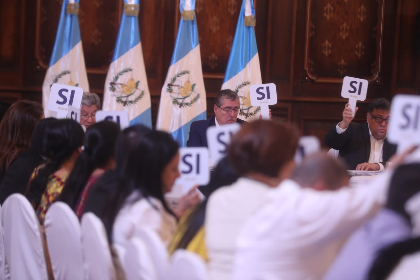 Funcionarios del Consejo Nacional de Desarrollo Urbano y Rural votan levantando un cartel con la palabra “Sí” durante la sesión en la que se aprobó la distribución de Q192 millones para los Codedes 2027.