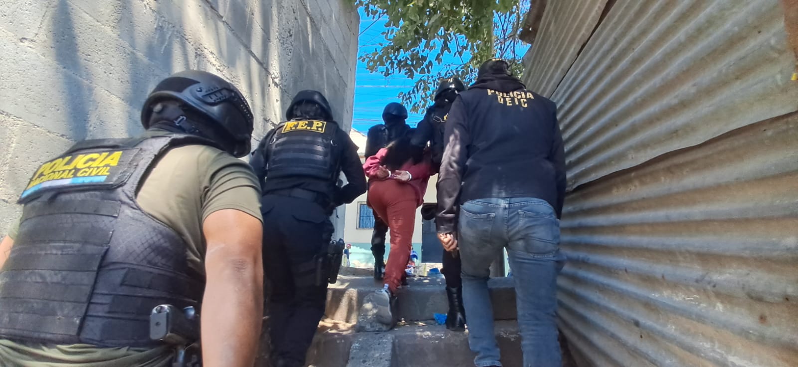 Agentes de la PNC escoltan a una presunta pandillera capturada durante un operativo realizado bajo el estado de sitio. (Foto Prensa Libre: PNC)