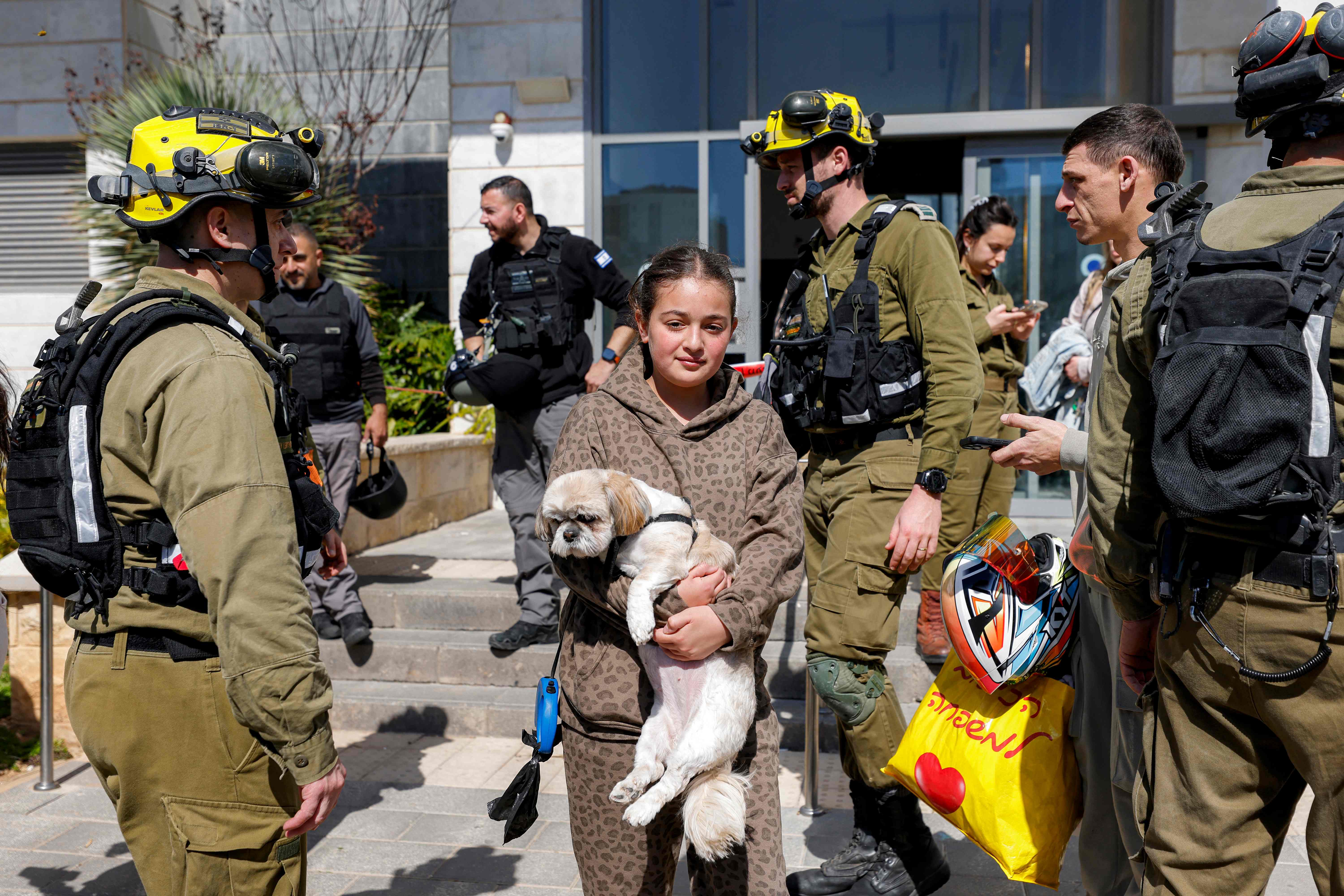 Una niña camina con un perro mientras residentes son evacuados de un edificio impactado por un proyectil en la ciudad de Tirat Carmel en el norte de Israel tras la escalada de ataques entre Estados Unidos y Israel a Irán. (Foto Prensa Libre: AFP)