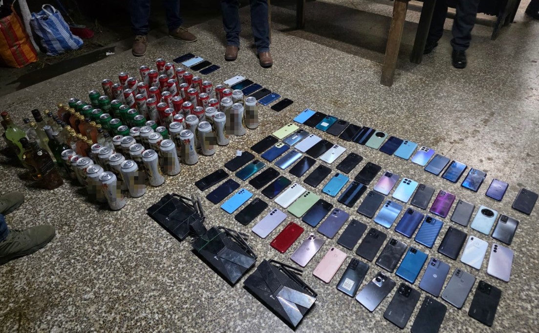 Agentes del Sistema Penitenciario muestran parte de los objetos incautados durante la requisa en Pavón: teléfonos celulares, armas de fuego, municiones y bebidas alcohólicas.