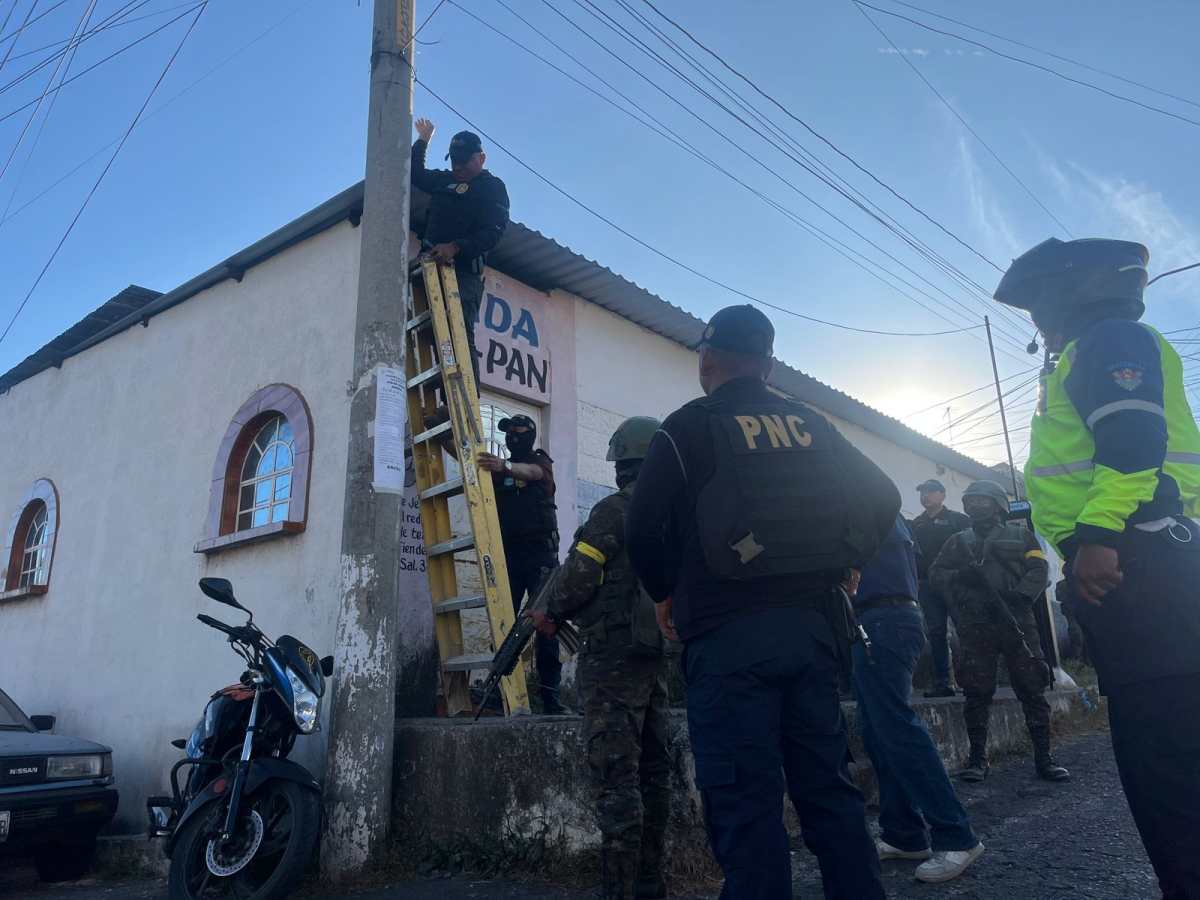 Agentes de la PNC retiran cámaras de videovigilancia instaladas por el Barrio 18 en postes de la colonia San Rafael II, zona 18. (Foto Prensa Libre: PNC)