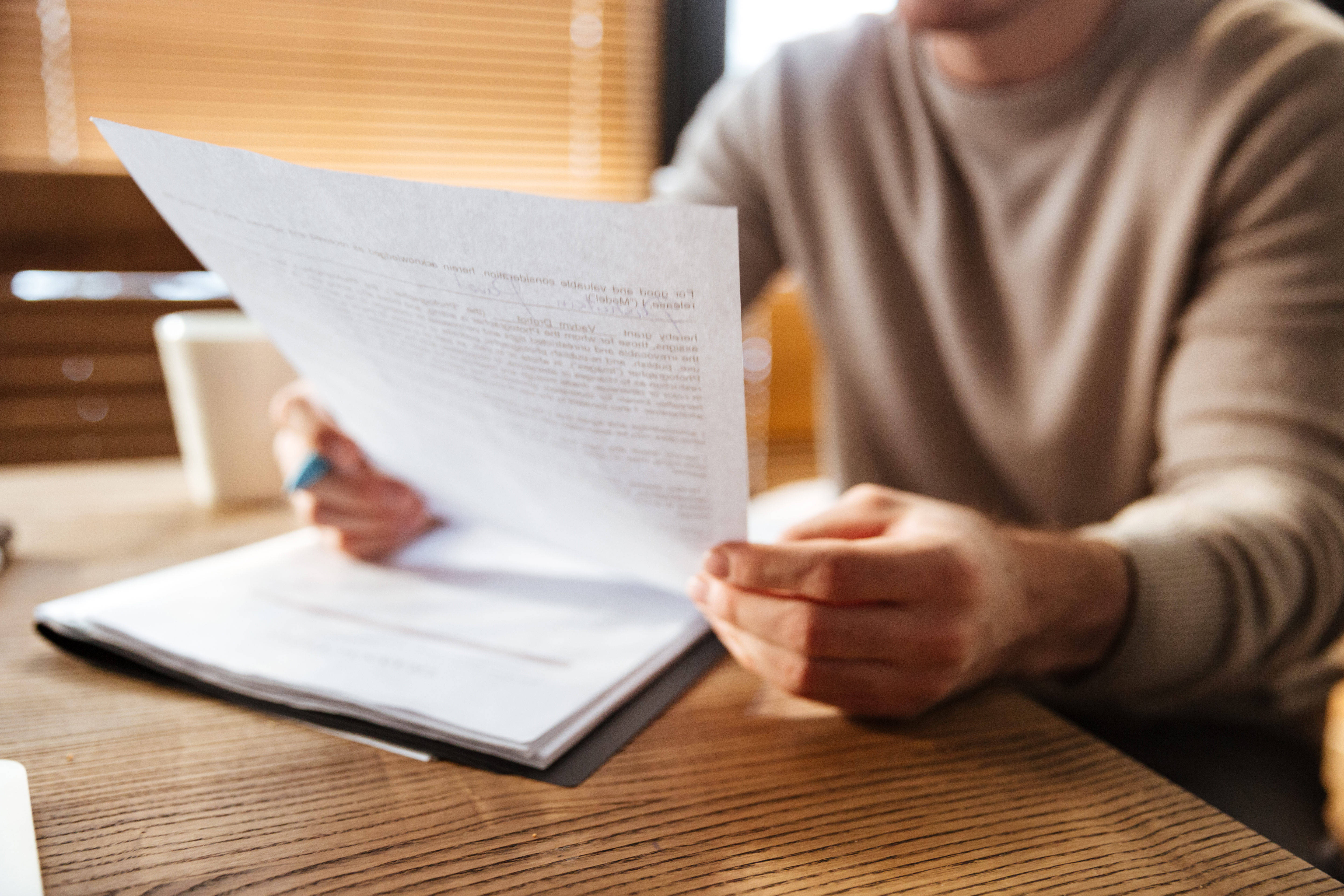 Cropped photo of attractive young man in office working with documents. Coworking.