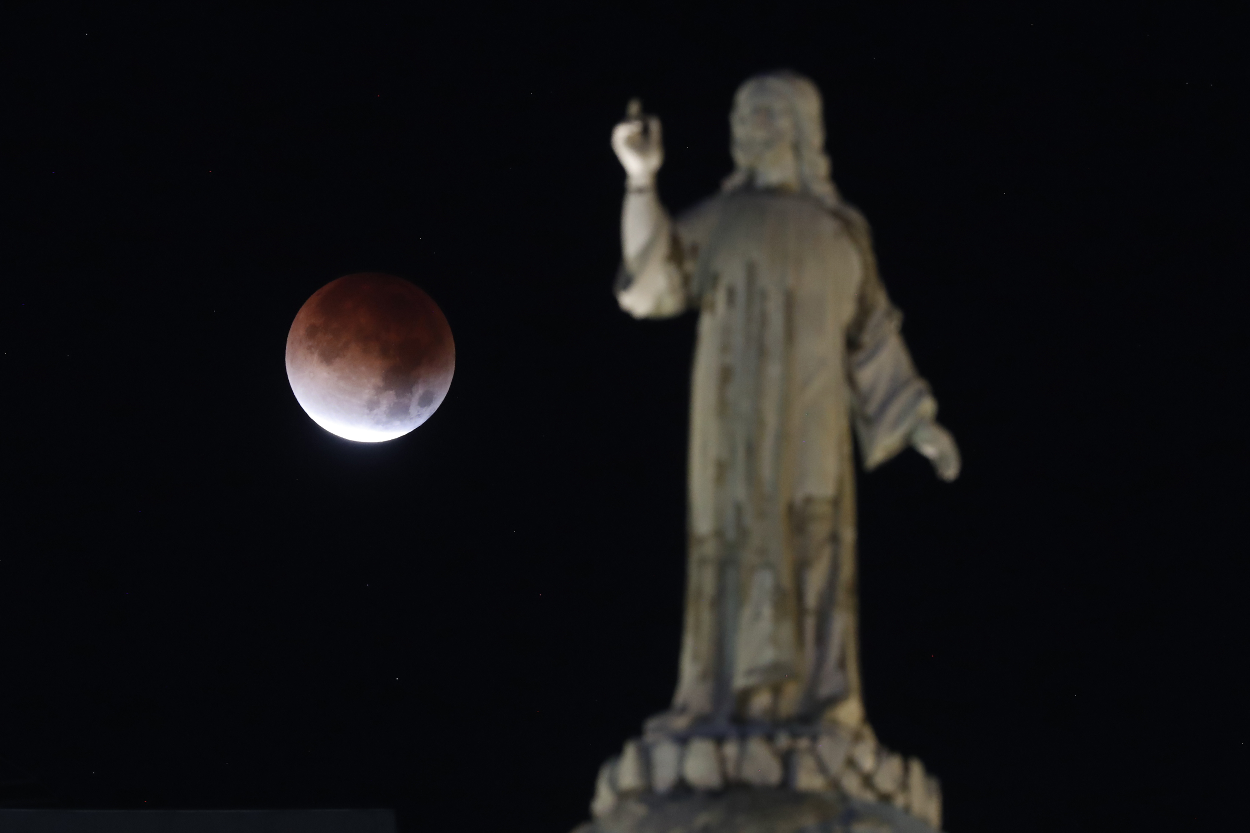 El eclipse lunar total y la llamada “Luna de Sangre” se observan sobre el Monumento al Divino Salvador del Mundo, San Salvador, El Salvador. (Foto Prensa Libre: EFE)