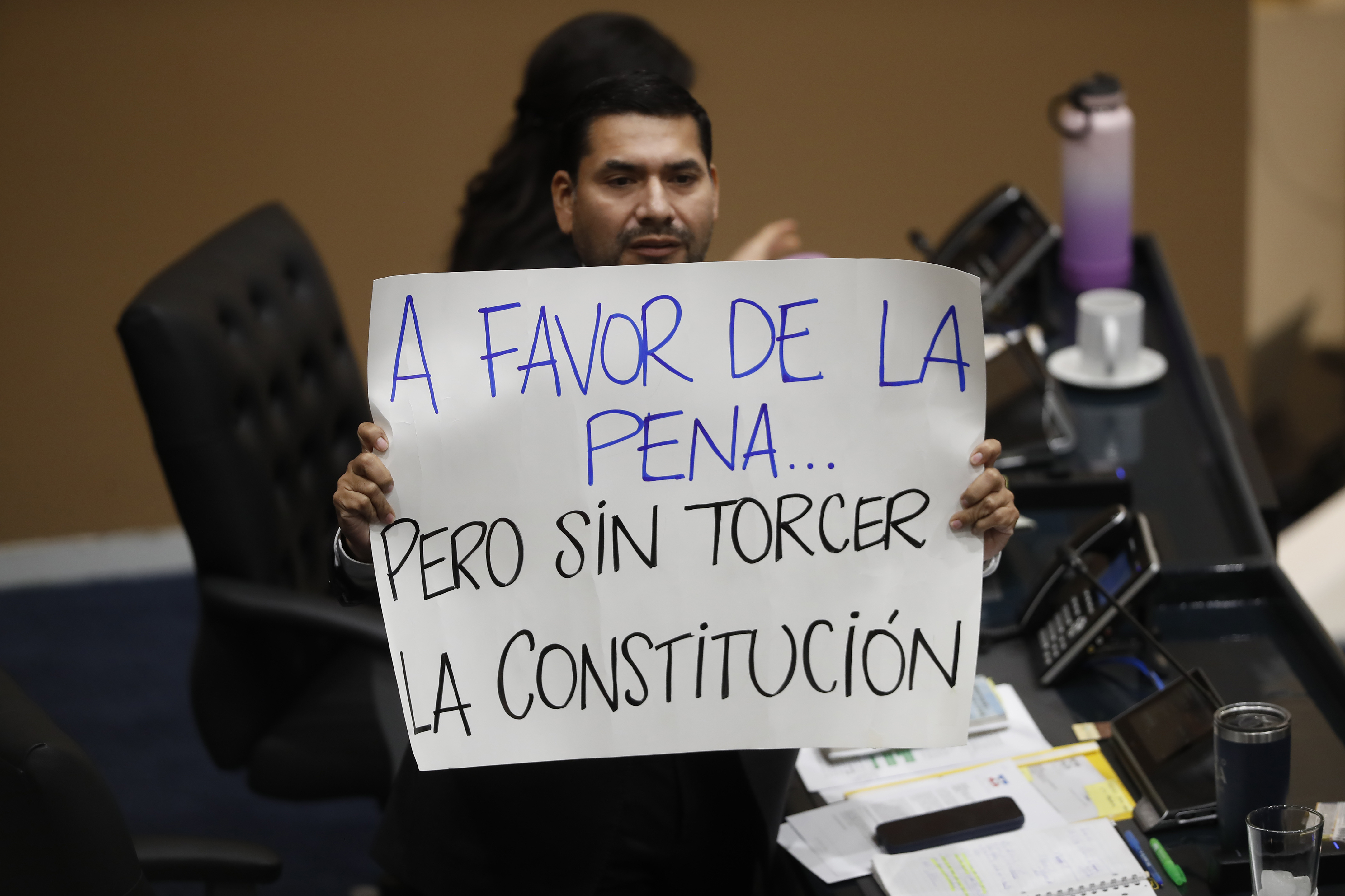 El diputado Francisco Lira muestra un letrero en el Congreso que ratificó reforma impulsada por Nayib Bukele con cadena perpetua. (Foto Prensa Libre: EFE)