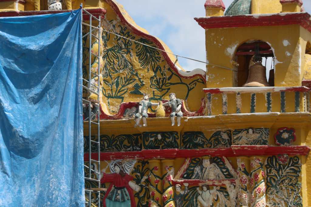 Parte superior del templo de San Andrés Xecul con desgaste en la pintura y detalles decorativos en la fachada.