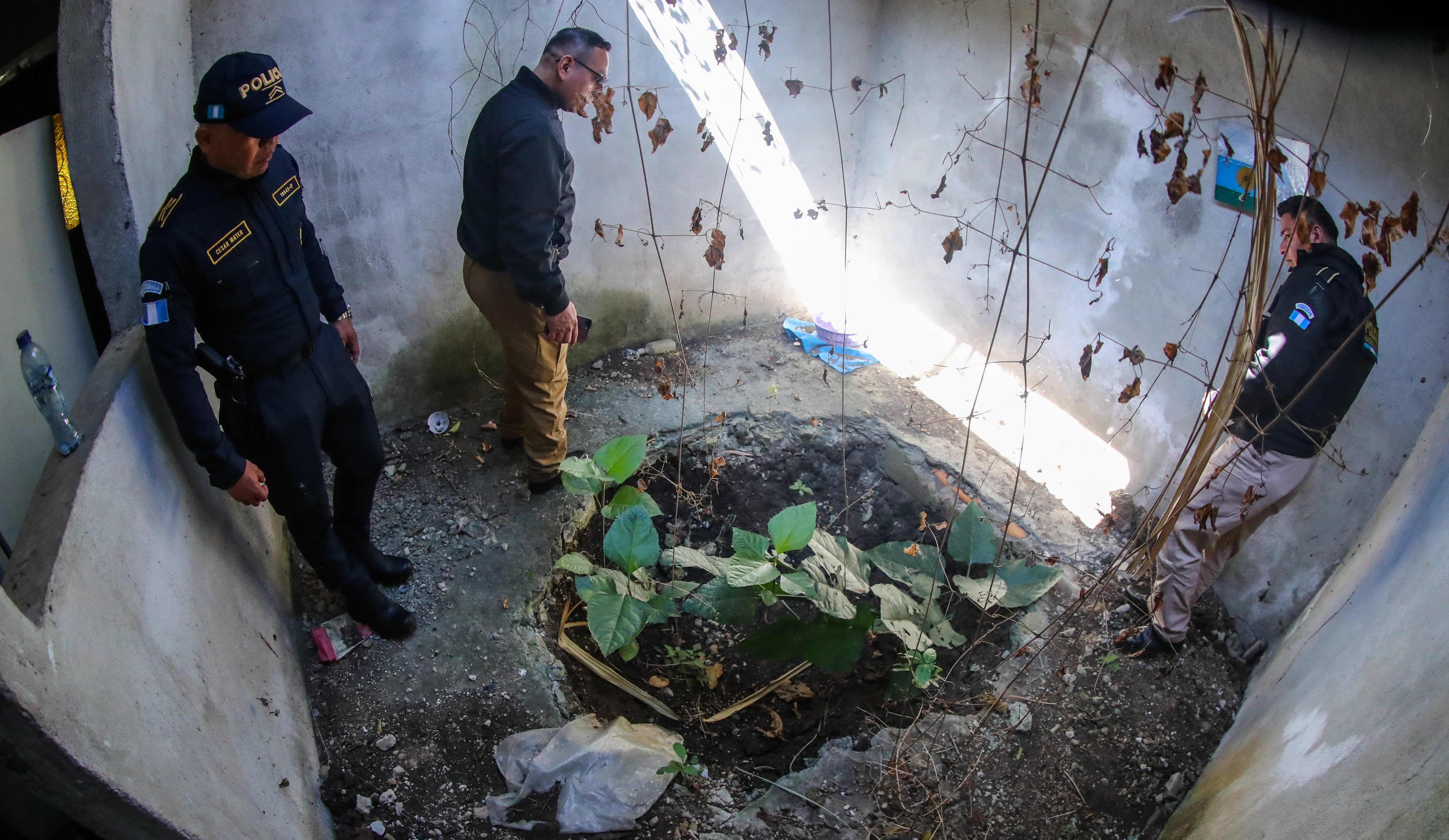 Tres policías observan la cavidad en la que se descubrió el cadáver d de un hombre en el 2014. La vivienda se ubica en el asentamiento Luz de Cristo, zona 12 de Villa Nueva. (Foto Prensa Libre: Juan Diego González)