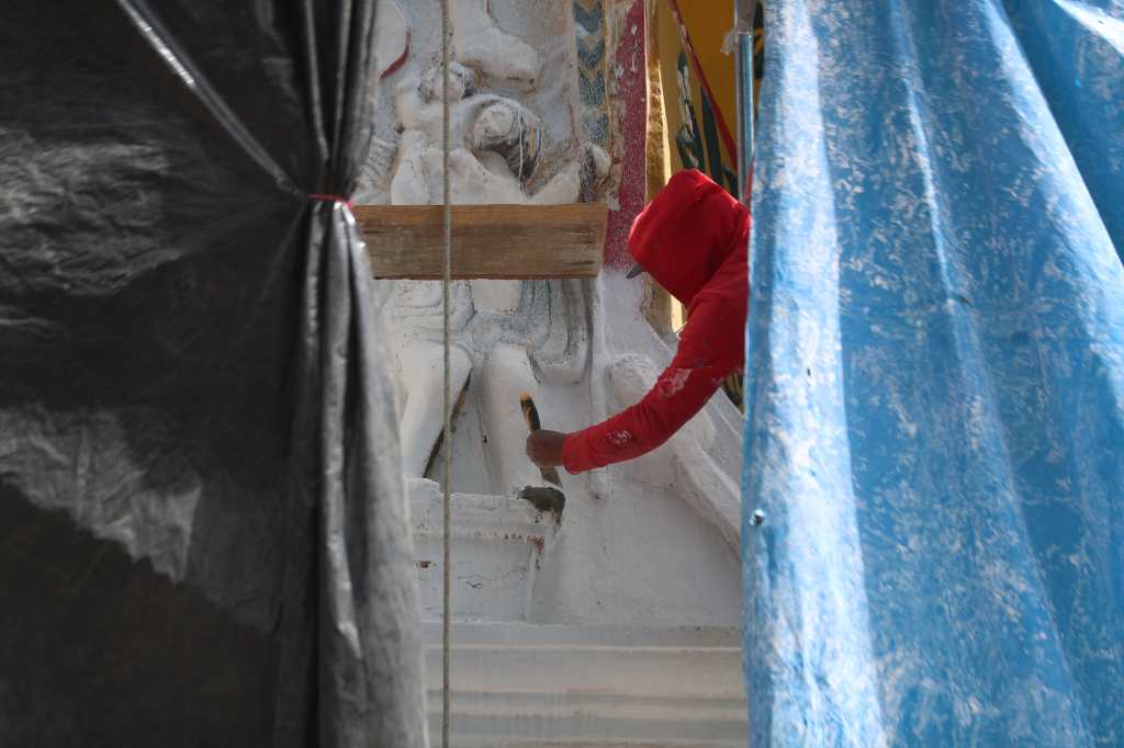 Trabajador pinta de blanco la fachada del templo de San Andrés Xecul durante los trabajos de restauración en Totonicapán.