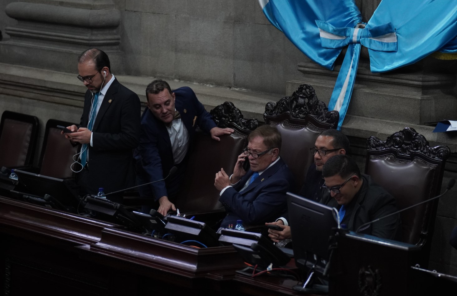Luis Contreras, al centro, conversa por teléfono, al igual que otros directivos, minutos antes de suspenderse la sesión del 3 de marzo. (Foto Prensa Libre: Javier González)