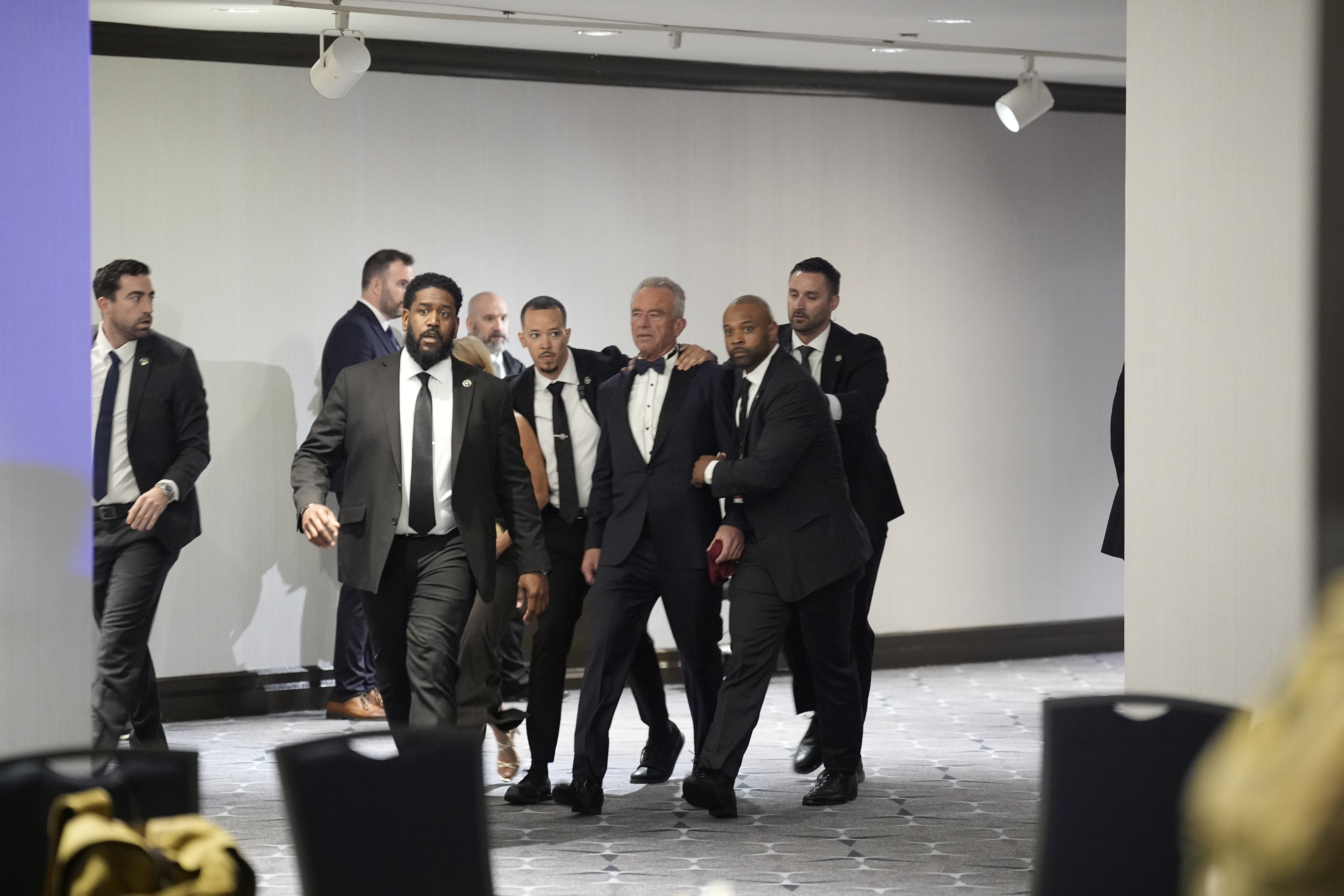 El secretario de Salud y Servicios Humanos, Robert Kennedy Jr., es evacuado por agentes de las fuerzas del orden durante la cena de la Asociación de Corresponsales de la Casa Blanca,'