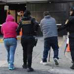 Agentes de la PNC trasladan a algunos de los implicados en la estructura de narcorepostería tras su detención. (Foto Prensa Libre: PNC)