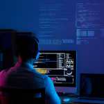 Developer working on code late at night, view from the back