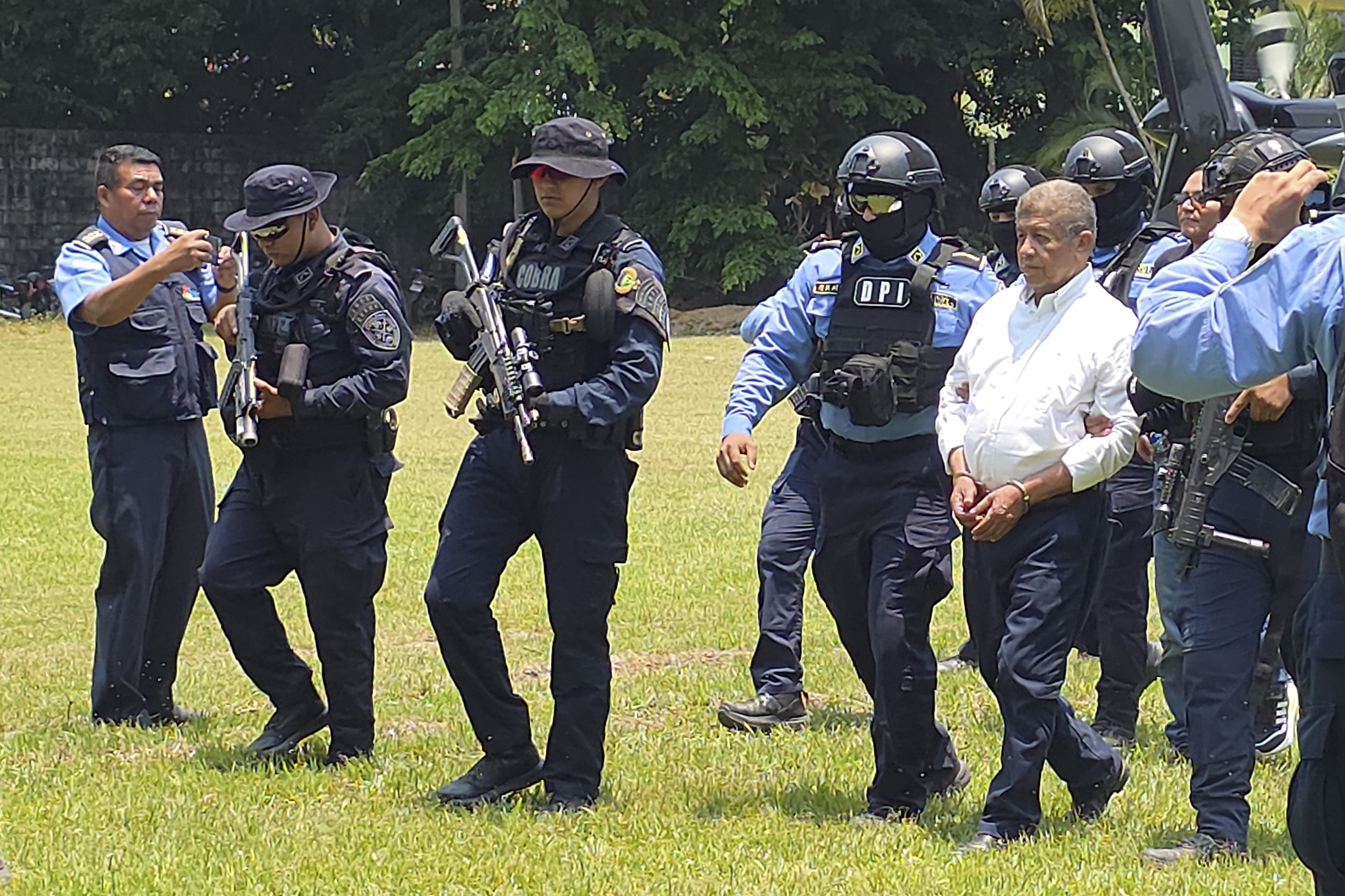 AME1330. LA CEIBA (HONDURAS), 12/05/2026.- El exalcalde de Tocoa Adán Fúnez (d), implicado en el asesinato del ambientalista Juan López, el 14 de septiembre de 2024, es escoltado en una base policial tras su captura este martes, en La Ceiba (Honduras). EFE/Cesar Fúnez/ MÁXIMA CALIDAD DISPONIBLE