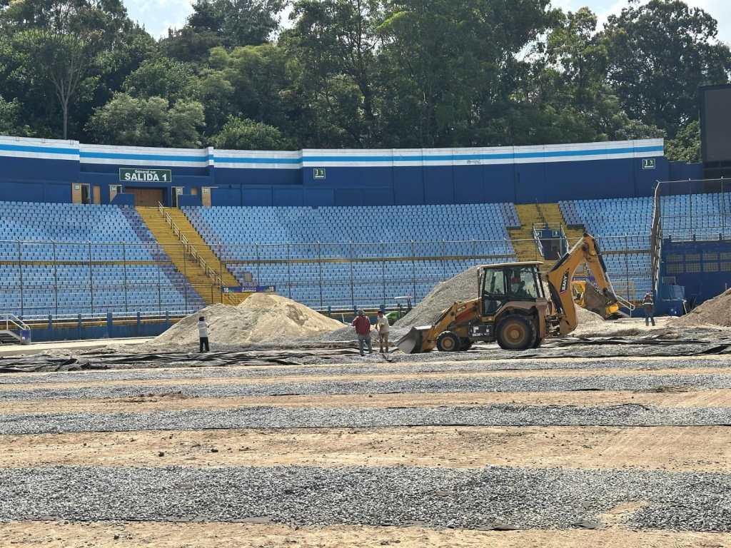 Panorámica del interior del estadio con la pista de tierra y trabajos pendientes de construcción.