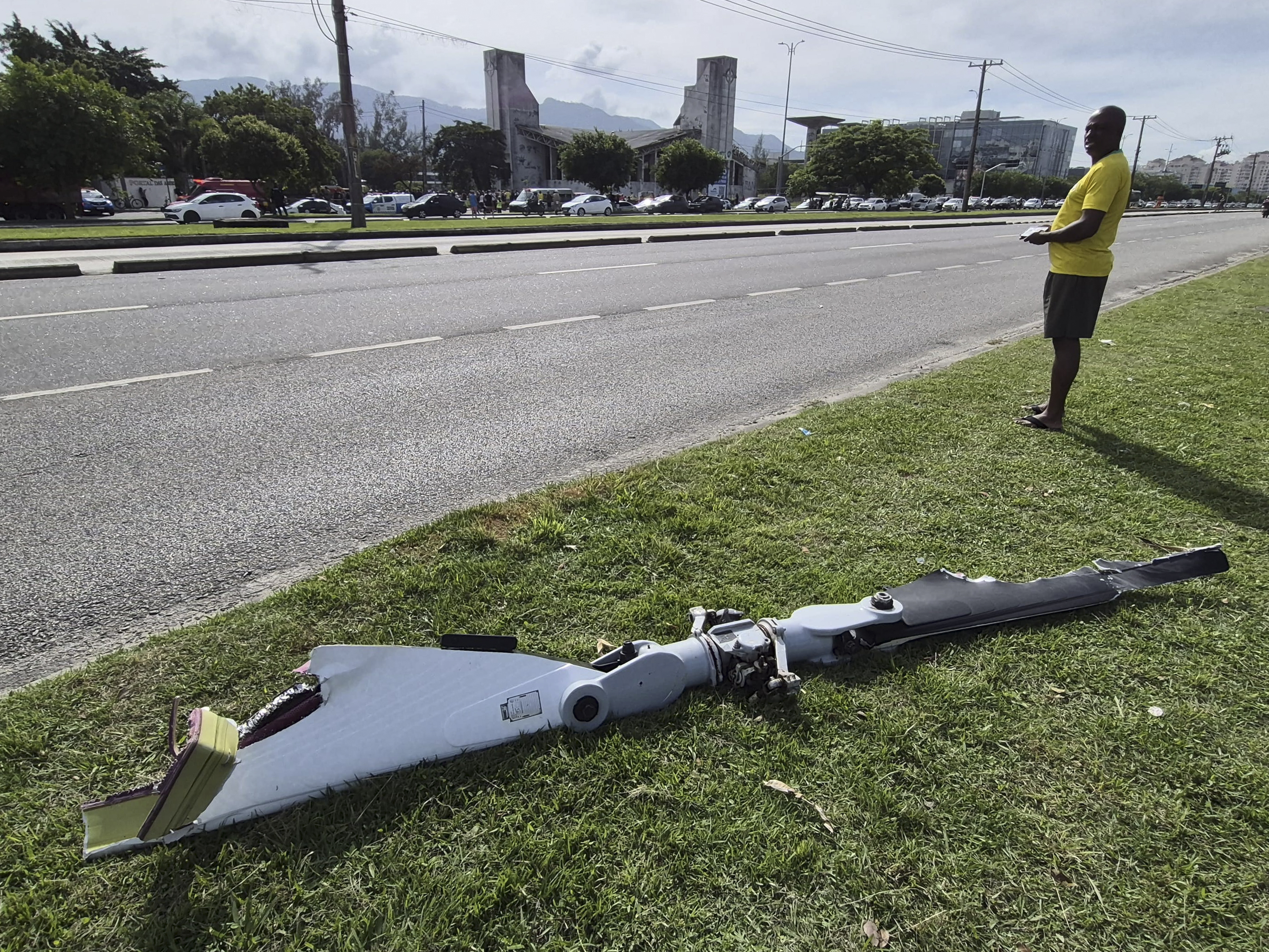 Fotografía cedida este domingo por Roberta Durço que muestra a una persona observando un fragmento de uno de los helicópteros que colisionaron en el barrio Recreio dos Bandeirantes, en Río de Janeiro, Brasil. (Foto Prensa Libre: EFE/ Roberta Durço) 