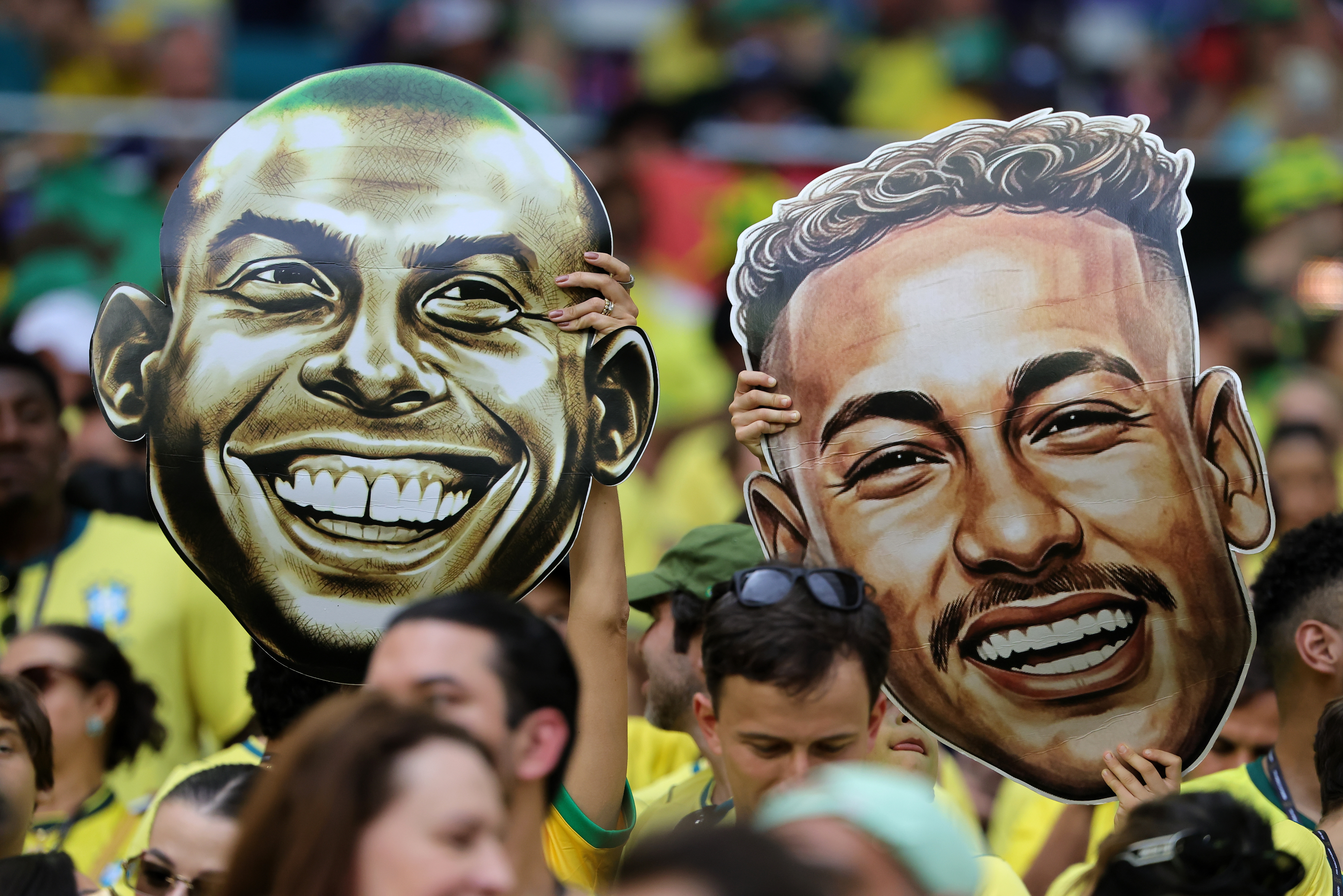 Aficionados de Brasil sostienen recortes de cabezas gigantes de Ronaldo Nazario (izq.) y Neymar Junior (der.) durante el partido de la fase de grupos de la Copa Mundial de la FIFA 2026 entre Escocia y Brasil.(Foto Prensa Libre: EFE).