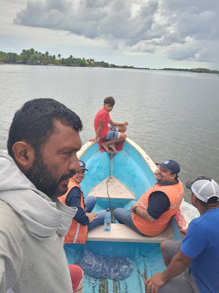 Antonio Flores y delegados de Conred se trasladan en lancha durante una inspección por las afectaciones del fuerte oleaje en El Jiote, Jutiapa.
