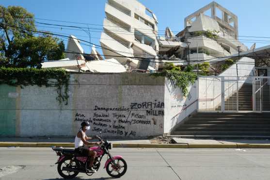 FOTODELDÍA AME8212. LA GUAIRA (VENEZUELA), 07/07/2026.- Una persona transita frente a un edificio colapsado con los nombres de personas desaparecidas durante el doble terremoto de magnitud 7,2 y 7,5 ocurrido el pasado 24 de Junio, este martes en La Guaira (Venezuela). EFE/ Xaume Olleros