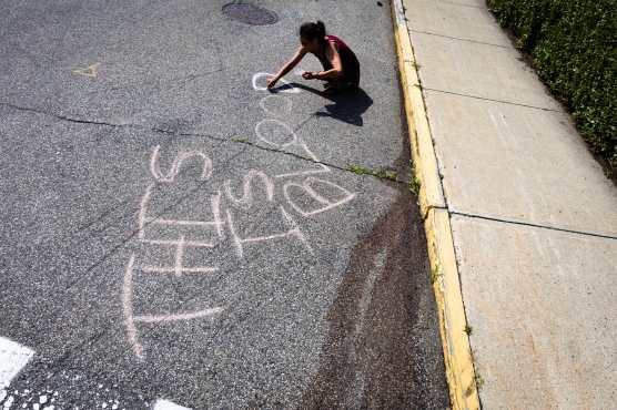 BIDDEFORD (United States), 13/07/2026.- A woman writes in chalk at the corner of Pool and Hill Streets at the site of a shooting involving ICE agents in which one person was killed, in Biddeford, Maine, USA, 13 July 2026. (Protestas) EFE/EPA/Troy R. Bennett