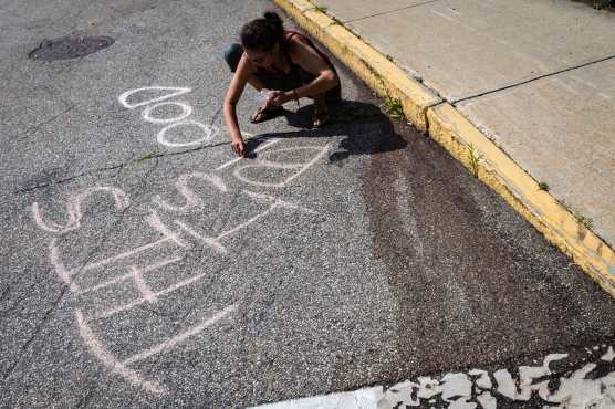 BIDDEFORD (United States), 13/07/2026.- A woman writes in chalk at the corner of Pool and Hill Streets at the site of a shooting involving ICE agents in which one person was killed, in Biddeford, Maine, USA, 13 July 2026. (Protestas) EFE/EPA/Troy R. Bennett