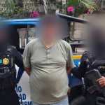 Agentes de la SGAIA de la Policía Nacional Civil trasladan a Erik Orlando Castillo Castillo, capturado en Santa Ana Huista, Huehuetenango, con fines de extradición a EE. UU., donde enfrenta ocho cargos relacionados con delitos sexuales. (Foto Prensa Libre: PNC)