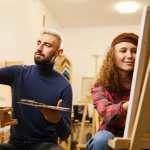 Man and woman draw paintings on easels