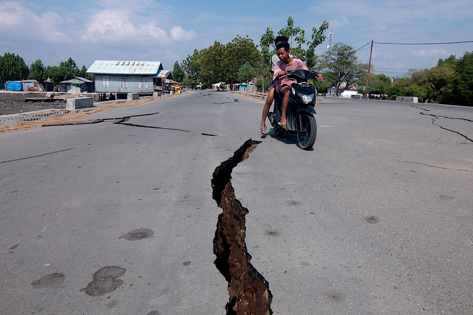 Motociclista pasa junto a una grieta en la carretera tras el terremoto de magnitud 7.7 en Indonesia.