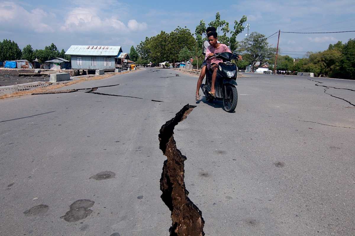 Motociclista pasa junto a una grieta en la carretera tras el terremoto de magnitud 7.7 en Indonesia.