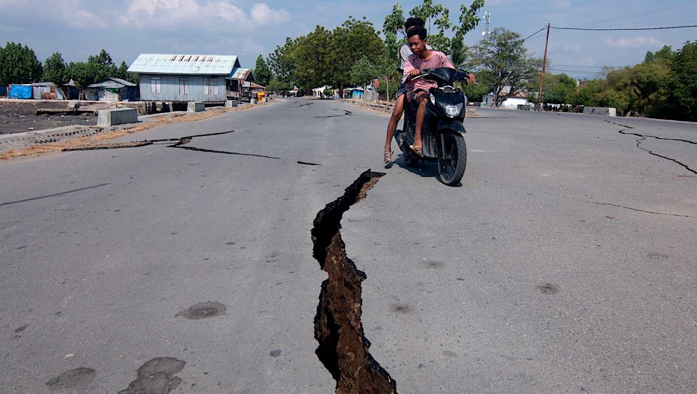 Motociclista pasa junto a una grieta en la carretera tras el terremoto de magnitud 7.7 en Indonesia.