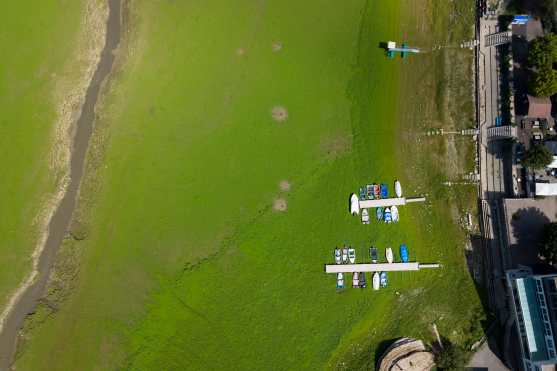 Les Brenets (Switzerland), 22/08/2026.- An aerial view shows stranded boats trapped in a mud-covered area with green grass on the dried out shore of the Lac des Brenets, its Swiss name, or Lac de Chaillexon, the French name, in Les Brenets, Switzerland, 22 August 2026. The lake sits on the Doubs river, a natural border between eastern France and western Switzerland. (sequía, Francia, Suiza) EFE/EPA/PETER KLAUNZER