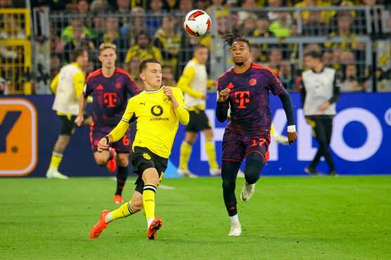 DORTMUND (Germany), 22/08/2026.- Giannis Konstantelias of Dortmund (L) in action against Michael Olise of Munich (R) during the Franz Beckenbauer Supercup match between Borussia Dortmund and Bayern Munich, in Dortmund, Germany, 22 August 2026. (Alemania) EFE/EPA/CHRISTOPHER NEUNDORF CONDITIONS - ATTENTION: The DFL regulations prohibit any use of photographs as image sequences and/or quasi-video.