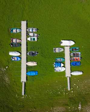 Les Brenets (Switzerland), 22/08/2026.- An aerial view shows stranded boats trapped in a mud-covered area with green grass on the dried out shore of the Lac des Brenets, its Swiss name, or Lac de Chaillexon, the French name, in Les Brenets, Switzerland, 22 August 2026. The lake sits on the Doubs river, a natural border between eastern France and western Switzerland. (sequía, Francia, Suiza) EFE/EPA/PETER KLAUNZER