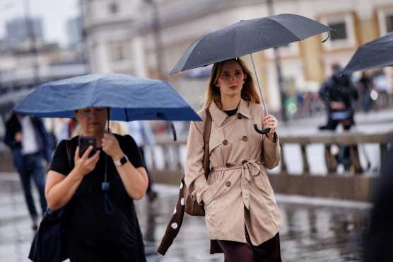 LONDON (United Kingdom), 27/08/2026.- Commuters holding umbrellas cross London Bridge during heavy rainfall in London, Britain, 27 August 2026. The heavy rain forecast comes as 71 percent of England and all of Wales remain officially in drought, even as the Met Office issues thunderstorm warnings across the country with up to a months worth of rain potentially falling on parched ground, bringing warnings of severe flash flooding. (sequía, Reino Unido, Londres) EFE/EPA/TOLGA AKMEN