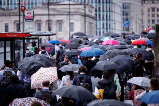 LONDON (United Kingdom), 27/08/2026.- Commuters holding umbrellas cross London Bridge during heavy rainfall in London, Britain, 27 August 2026. The heavy rain forecast comes as 71 percent of England and all of Wales remain officially in drought, even as the Met Office issues thunderstorm warnings across the country with up to a months worth of rain potentially falling on parched ground, bringing warnings of severe flash flooding. (sequía, Reino Unido, Londres) EFE/EPA/TOLGA AKMEN