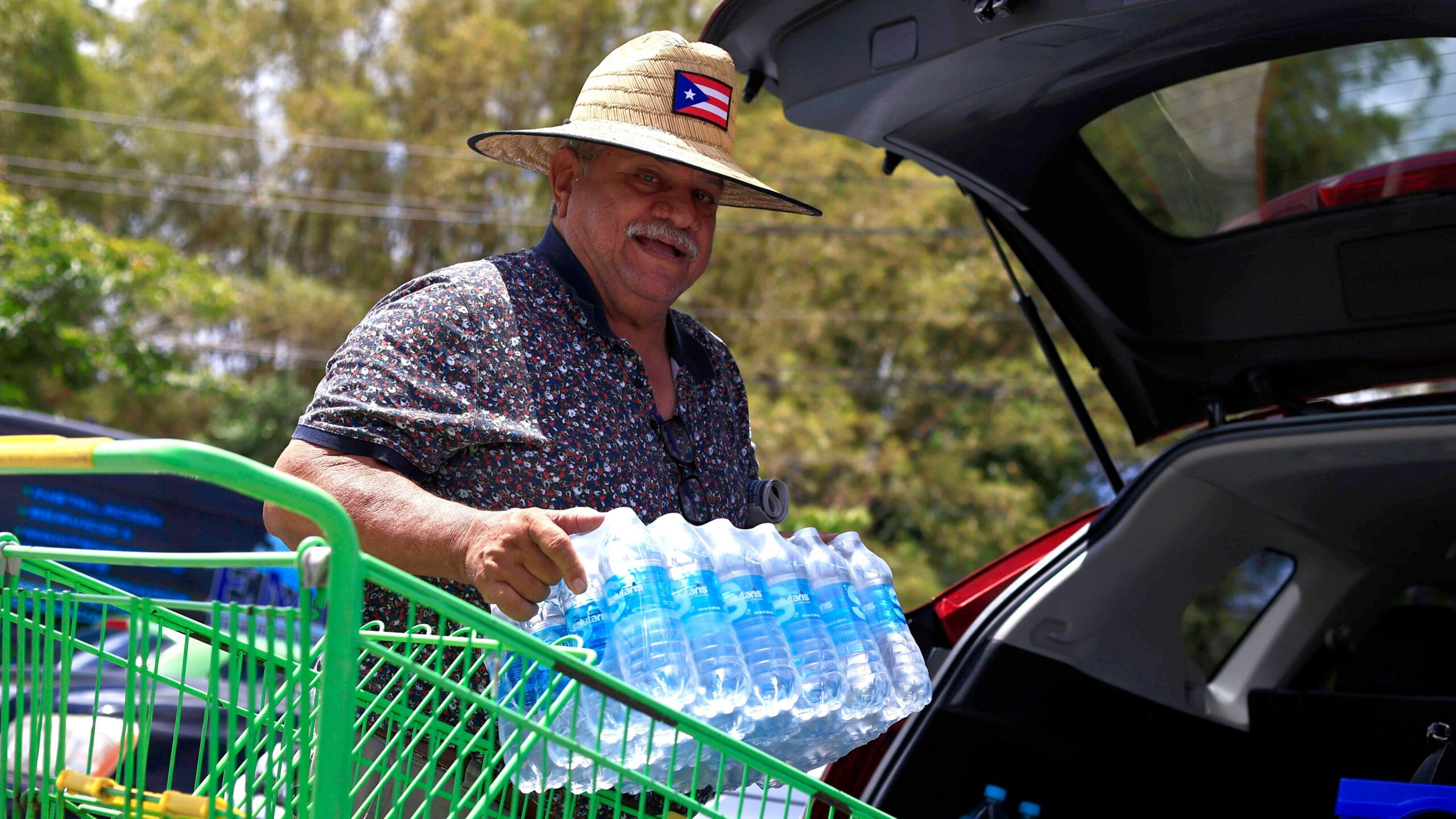 Una mujer llena un gran recipiente de agua en un grifo público.