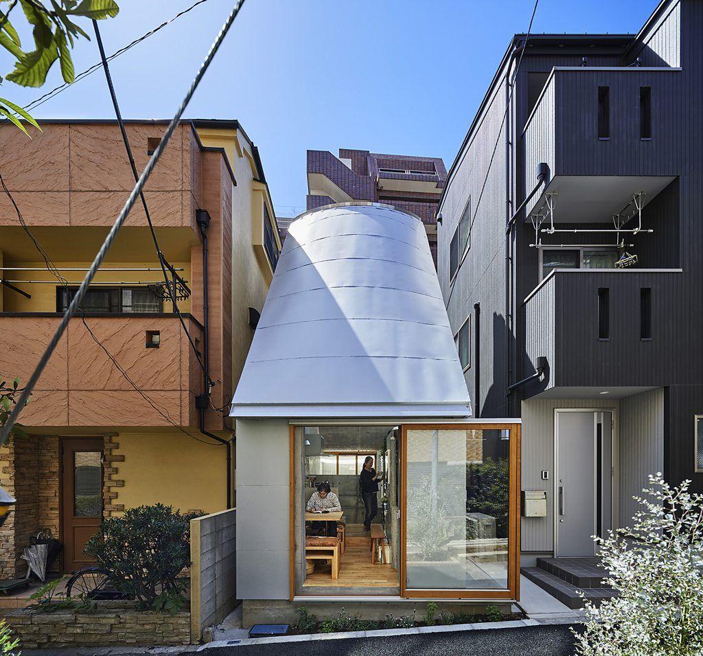 Casa moderna de una planta rodeada de árboles, con grandes ventanales, jardín de césped y senderos de madera curvos.
