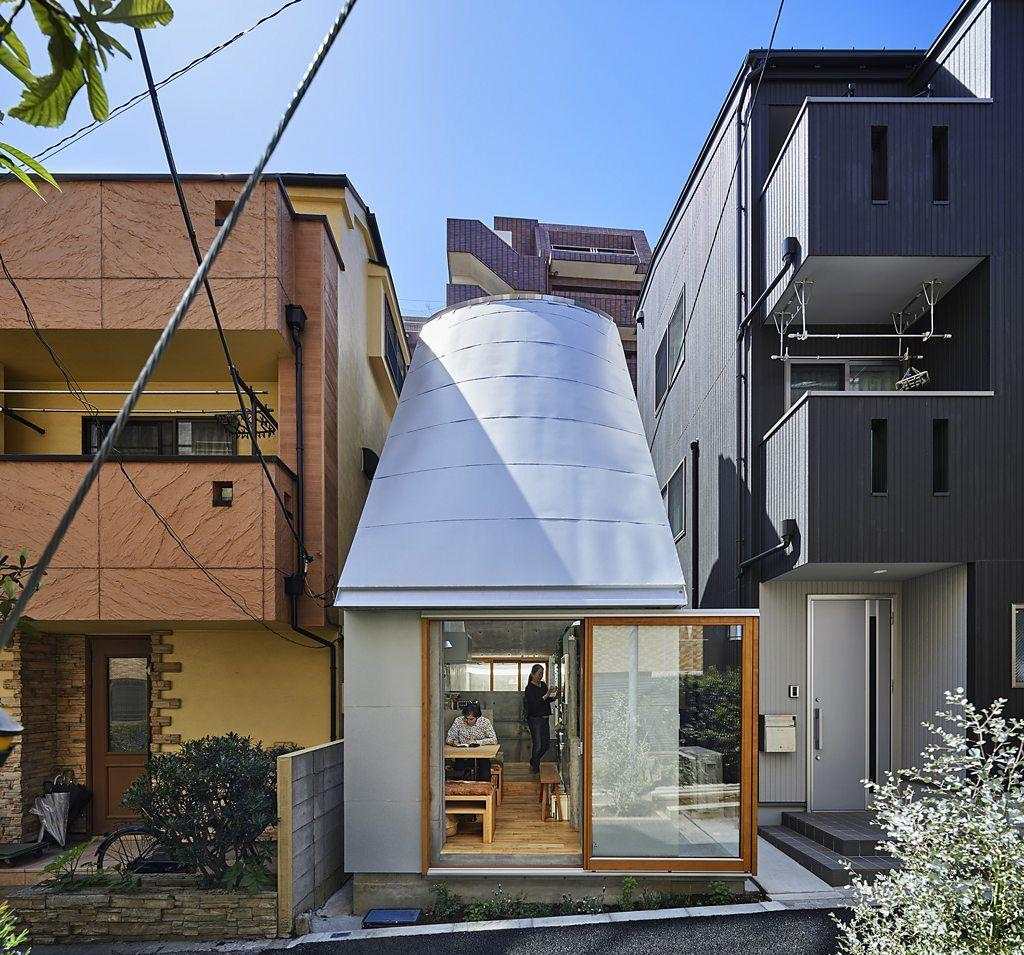 Casa moderna de una planta rodeada de árboles, con grandes ventanales, jardín de césped y senderos de madera curvos.