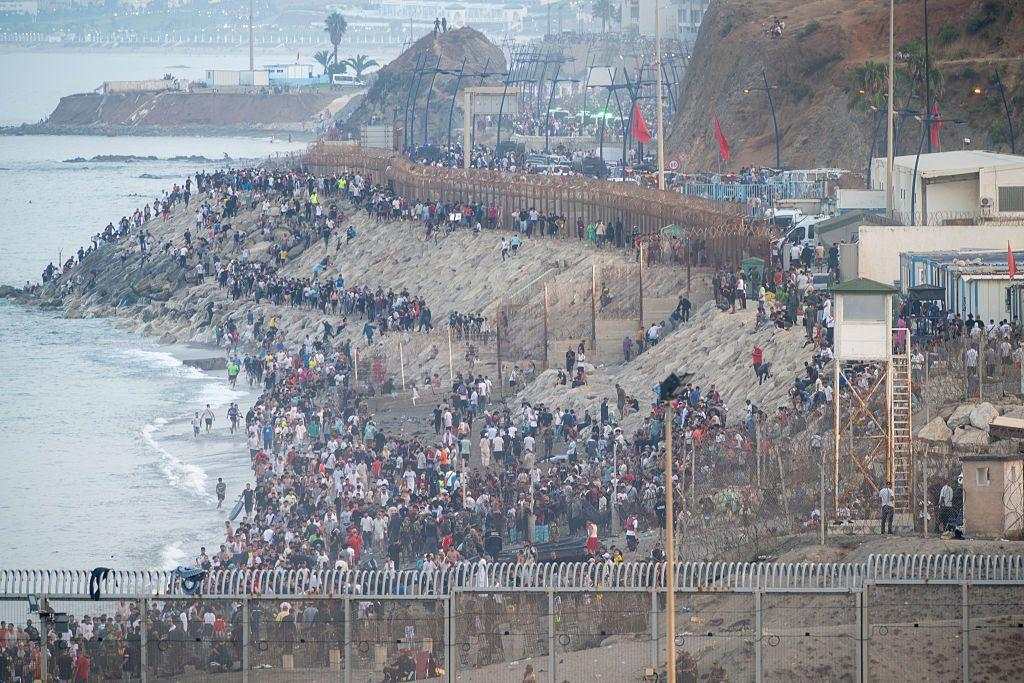 Agentes de policía y soldados españoles escoltan a un numeroso grupo de migrantes en Ceuta hasta la frontera para devolverlos a Marruecos.