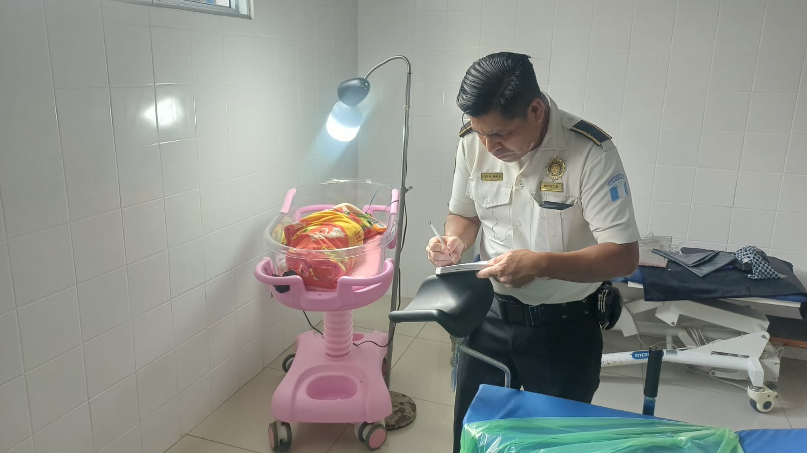 Un agente de la PNC permanece junto a la recién nacida en el Hospital Regional de Cobán, donde la bebé recibe atención médica. (Foto Prensa Libre: Cortesía)