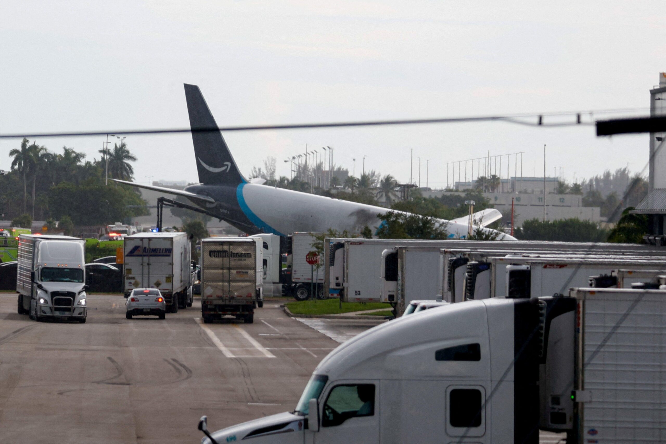 Un avión ladeado al lado de una fila de camiones
