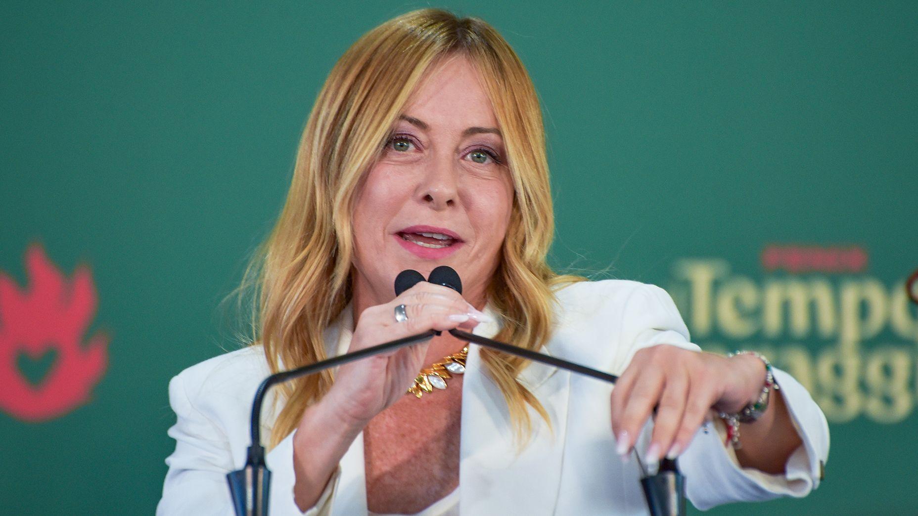 La primera ministra de Italia, Giorgia Meloni, que luce una larga melena rubia y viste una chaqueta blanca, habla ante un micrófono en un acto celebrado el 20 de septiembre.