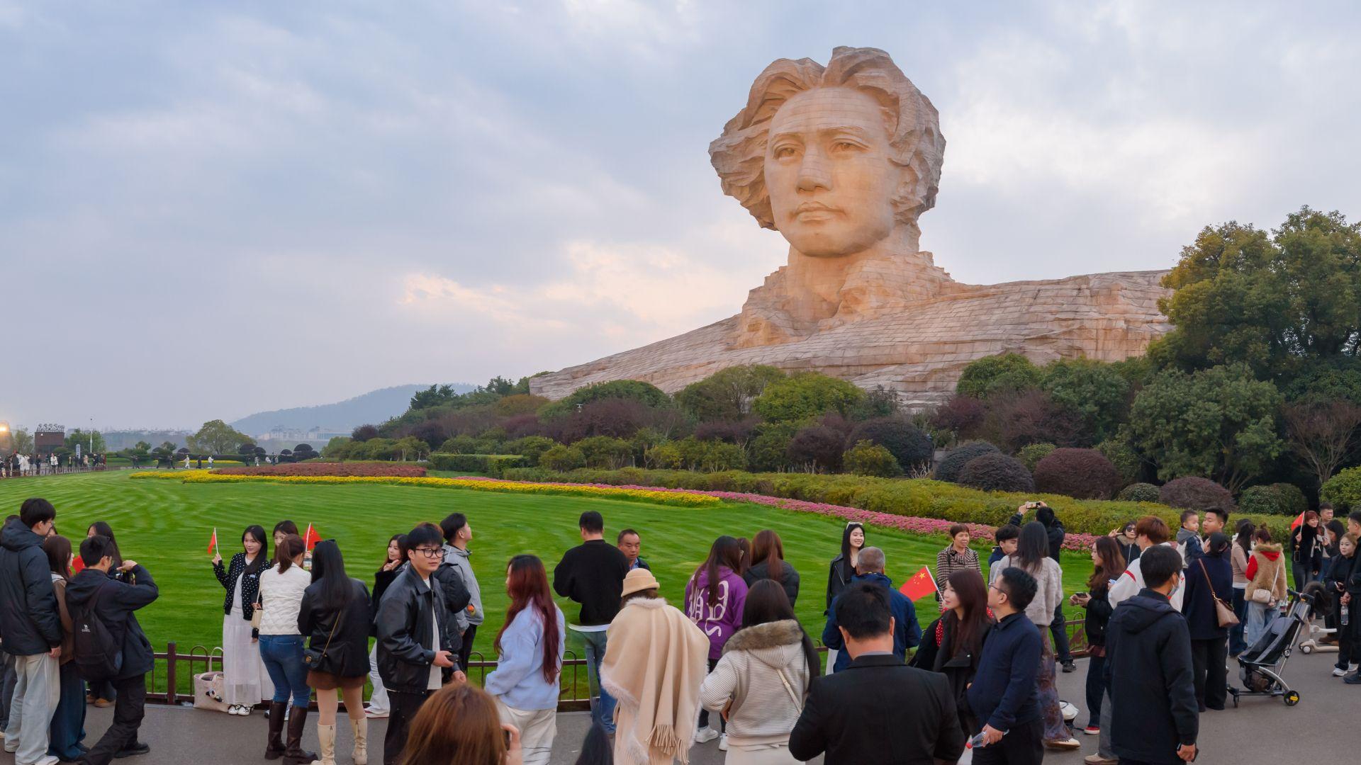 Una imagen de Mao en la pantalla de un teléfono celular se superpone a una foto de varias personas caminando, tratada con colores azul y rojo, con indicios de la bandera china en el extremo derecho.