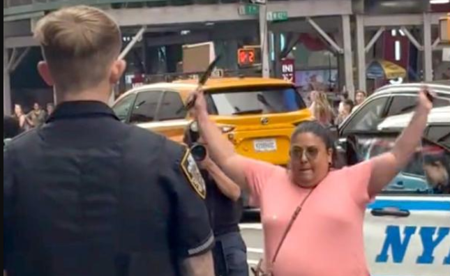 Pamela Cisneros sostiene dos cuchillos mientras se enfrenta a agentes de la Policía de Nueva York en Times Square. (Foto Prensa Libre: Captura de pantalla)