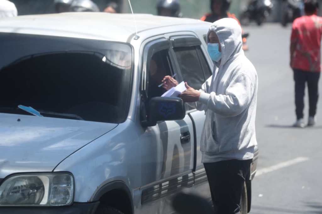 Persona solicita firmas a un conductor durante un bloqueo en el ingreso de la colonia Bethania, en la zona 7 de ciuidad de Guatemala