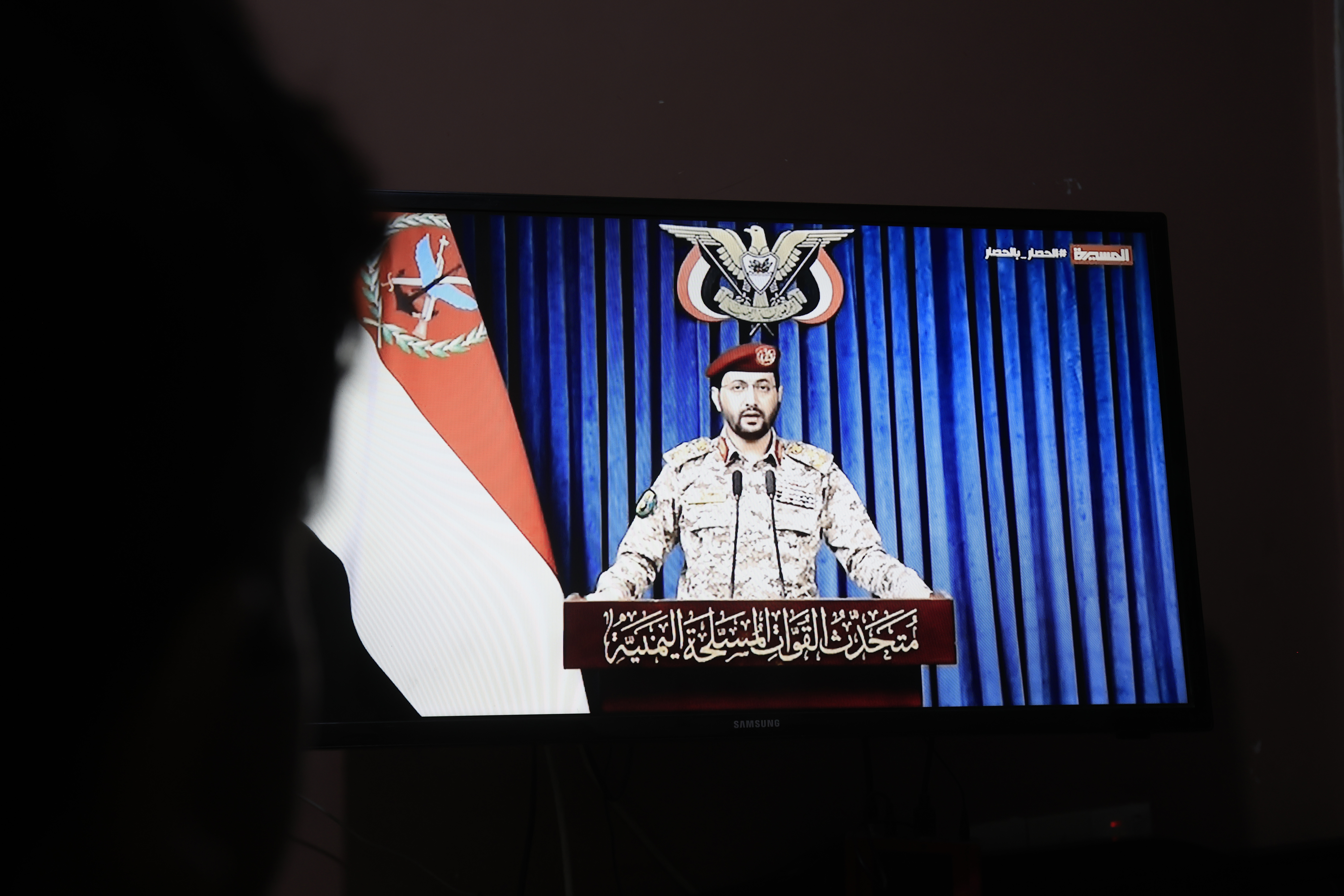SANA'A (Yemen), 11/10/2026.- A person watches Houthi military spokesman Yahya Sarea delivering a televised statement in Sana'a, Yemen, 11 October 2026. Yemen's Houthis claimed responsibility for four missile-drone attacks on Saudi positions, including a missile attack that struck King Khalid Airport in Riyadh, killing 12 people, including four Saudi nationals, and injuring 309 others, according to Houthi military spokesman Yahya Sarea. (Arabia Saudita) EFE/EPA/YAHYA ARHAB