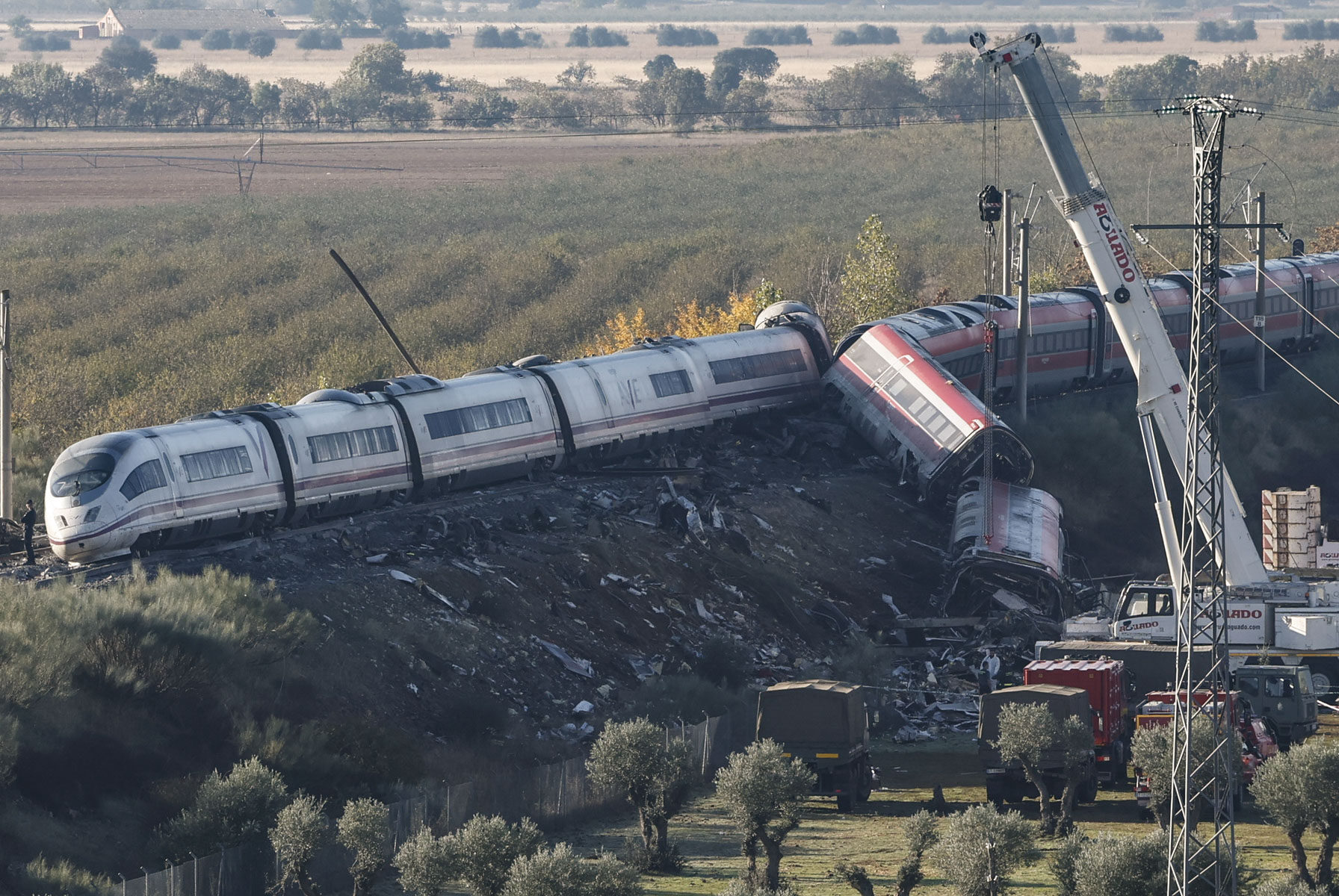 Camiones del ejército y grúas pesadas trabajan en los convoyes de los trenes que colisionaron en Urda, Toledo, un día después del suceso. (Foto Prensa Libre: EFE/ J.J.Guillen).