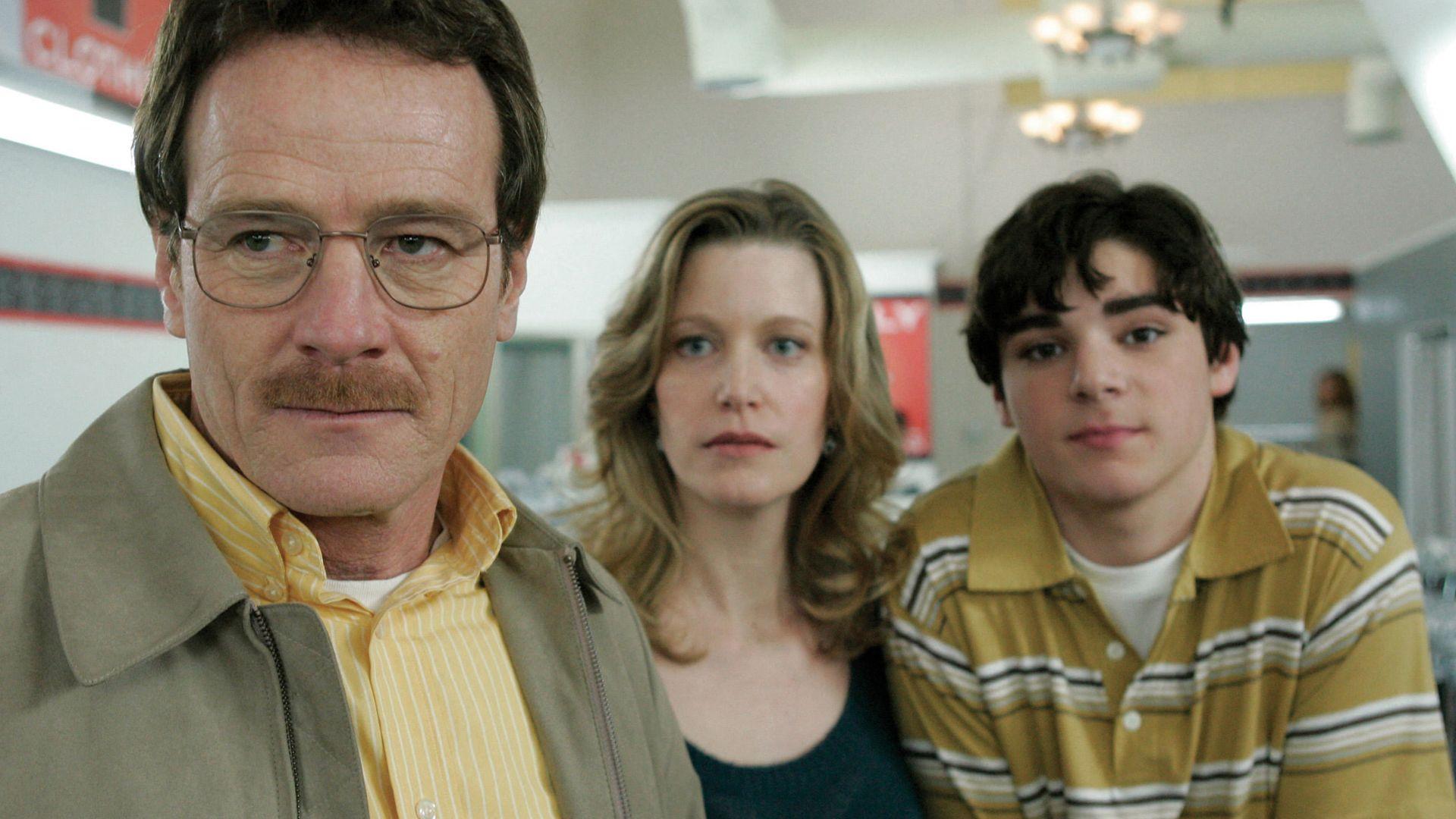 Bryan Cranston y RJ Mitte visten un traje negro y sonríen a la cámara. Ambos sostienen una estatuilla.