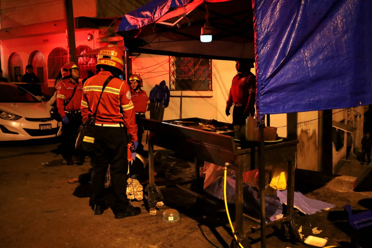 Agentes de la Policía Nacional Civil y elementos de los Bomberos Municipales permanecen en el lugar donde ocurrió un ataque armado en un puesto de comida de la colonia La Palmita, zona 5 capitalina. (Foto Prensa Libre: CBM)