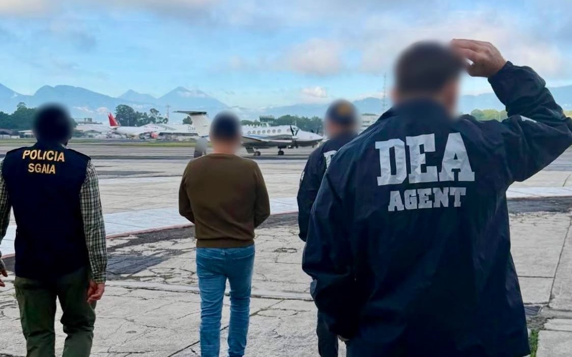 Kevin Raymundo Roque Contreras, requerido por una corte de Texas por delitos relacionados con el narcotráfico, aparece junto a agentes de la DEA durante su extradición a Estados Unidos este viernes 16 de octubre. (Foto Prensa Libre: Tomada de @usembassyguate)