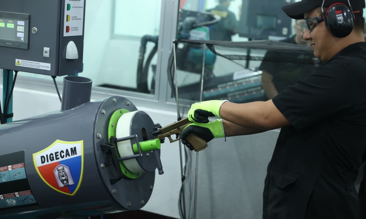 Un técnico de la Digecam manipula un arma de fuego en un equipo de recuperación de proyectiles del laboratorio de huella balística inaugurado por la institución. (Foto Prensa Libre: Esbin García)
